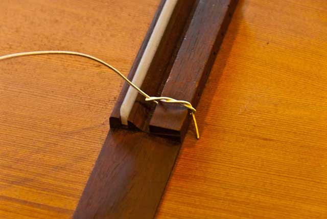 A typical knot on the bridge of a classic guitar